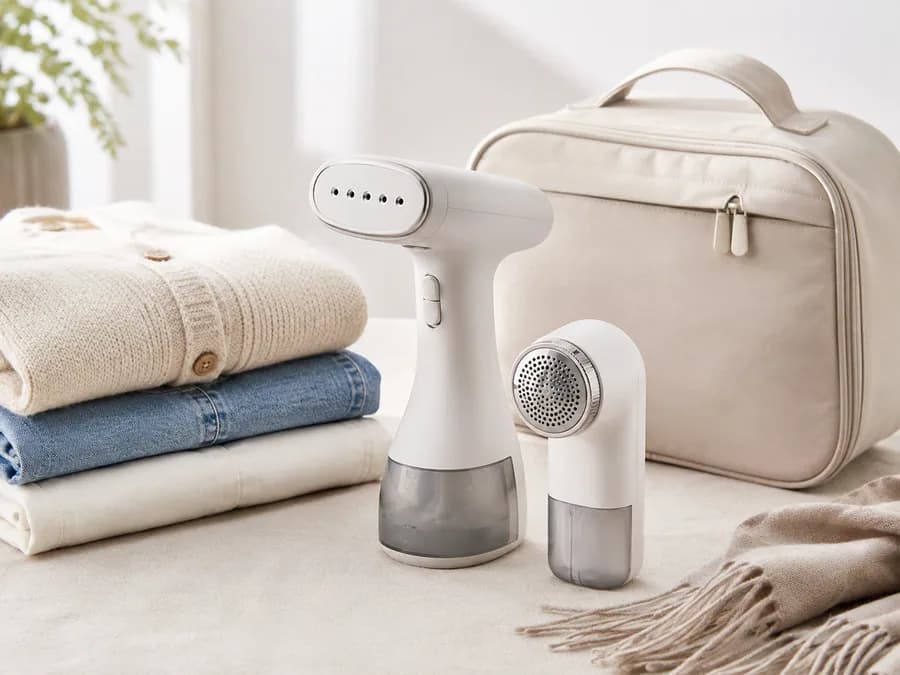 Mini Garment Steamer and Lint Remover Product Image Mini garment steamer and lint remover with folded clothes and travel bag